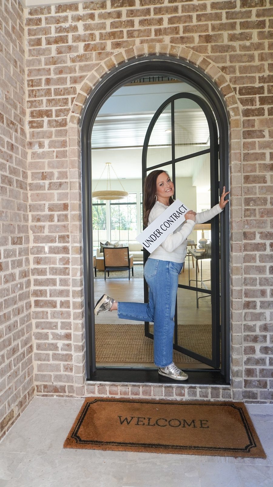 Kellee holding an Under Contract sign in an arched front doorway